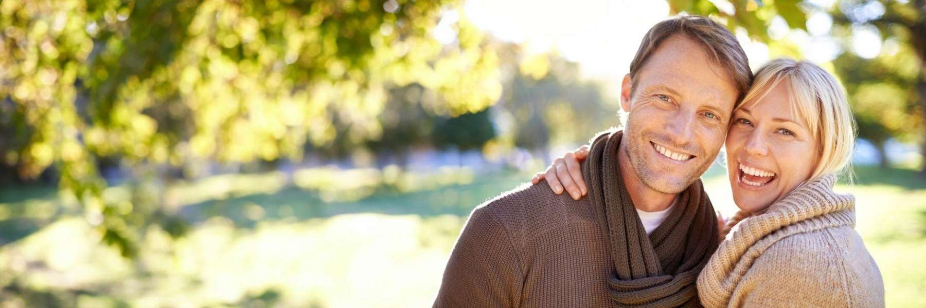 Happy couple outdoors smiling confidently after receiving Dental Implants